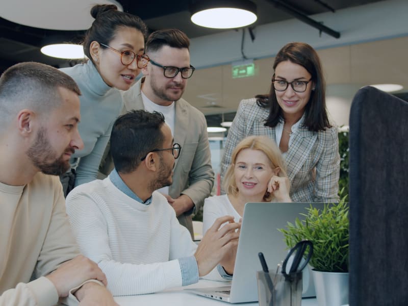 A team collaborating around a laptop in a modern open-plan office