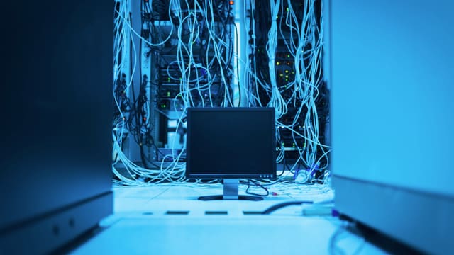 A server rack with dense network cabling in a blue-lit data center